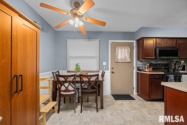 237 Colony Dr, Davenport, IA 52806 - kitchen featuring stainless steel microwave, black range with electric stovetop, ceiling fan, a textured ceiling, and wainscoting