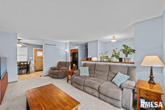 237 Colony Dr, Davenport, IA 52806 - living area with light colored carpet, a textured ceiling, a ceiling fan, and baseboards