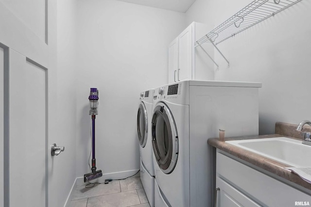 4241 Colorado Dr, Bettendorf, IA 52722 - laundry area featuring separate washer and dryer, cabinet space, light tile patterned flooring, and baseboards