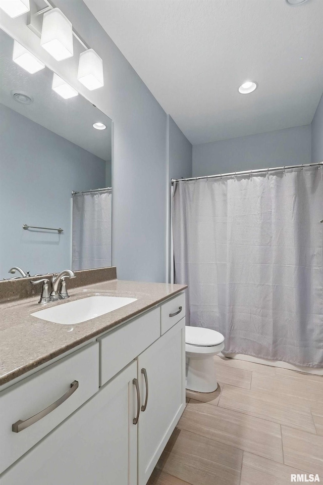 4241 Colorado Dr, Bettendorf, IA 52722 - bathroom with vanity, toilet, wood finished floors, and recessed lighting