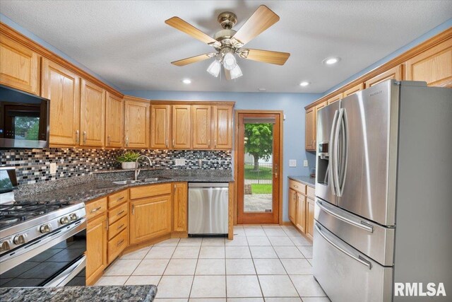 859 45th Ave, East Moline, IL 61244 - kitchen featuring stainless steel appliances, a sink, tasteful backsplash, light tile patterned floors, and dark stone countertops