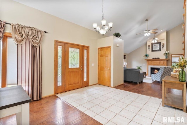 859 45th Ave, East Moline, IL 61244 - foyer with a warm lit fireplace, vaulted ceiling, a chandelier, light wood-style flooring, and a ceiling fan