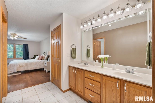 859 45th Ave, East Moline, IL 61244 - bathroom with connected bathroom, double vanity, tile patterned floors, a ceiling fan, and a textured ceiling