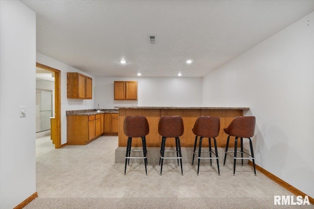 859 45th Ave, East Moline, IL 61244 - kitchen featuring baseboards, brown cabinetry, a breakfast bar area, light carpet, and recessed lighting