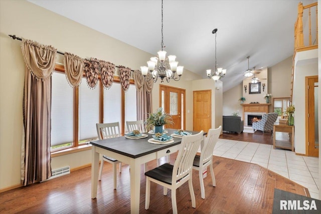 859 45th Ave, East Moline, IL 61244 - dining area featuring a lit fireplace, a chandelier, vaulted ceiling, light wood-type flooring, and ceiling fan