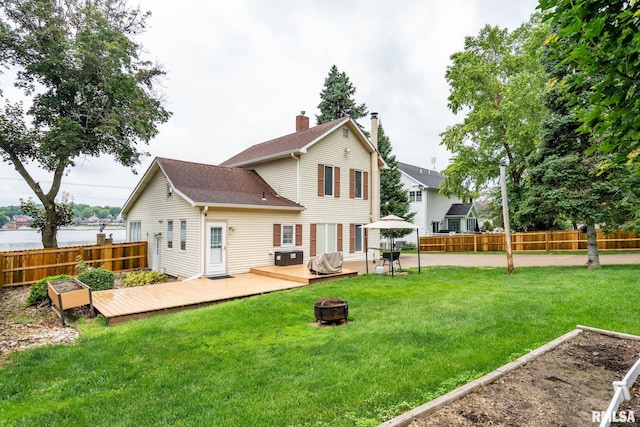 608 S Main St, Port Byron, IL 61275 - back of house with an outdoor fire pit, a fenced backyard, a wooden deck, a chimney, and a vegetable garden