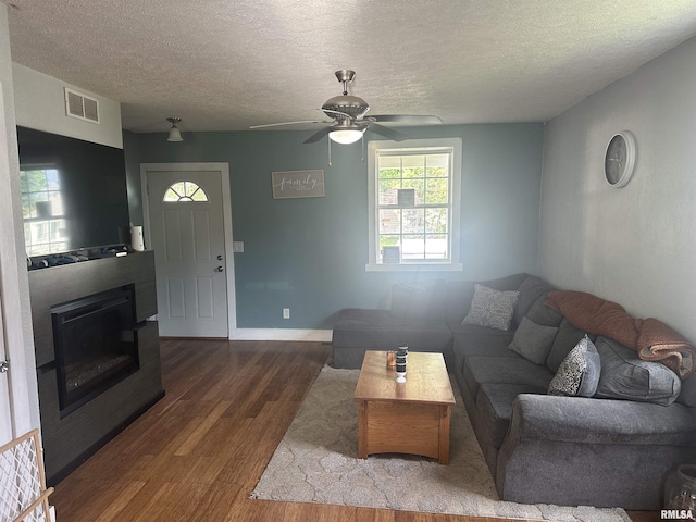 119 S Elm St, Williamsfield, IL 61489 - living area with wood finished floors, a textured ceiling, ceiling fan, a glass covered fireplace, and baseboards