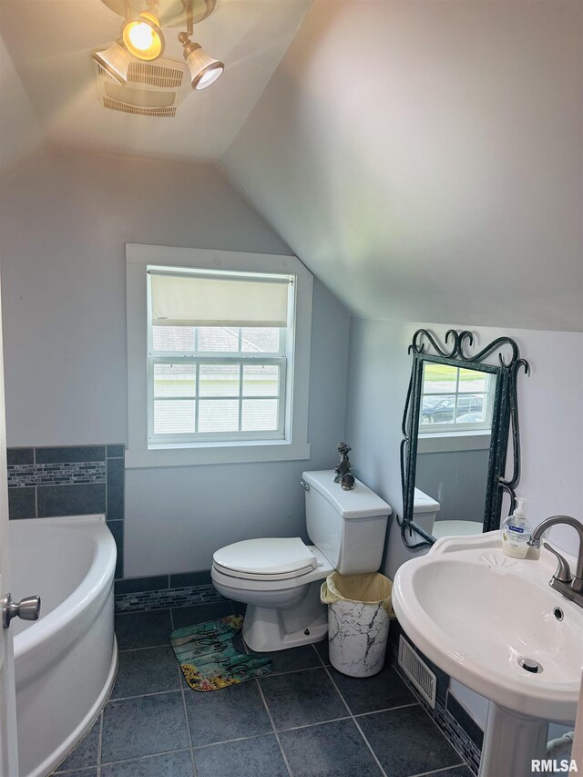 119 S Elm St, Williamsfield, IL 61489 - bathroom with lofted ceiling, a bath, toilet, a sink, and tile patterned floors