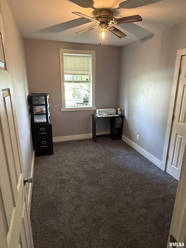 119 S Elm St, Williamsfield, IL 61489 - unfurnished bedroom with dark carpet, baseboards, and a ceiling fan