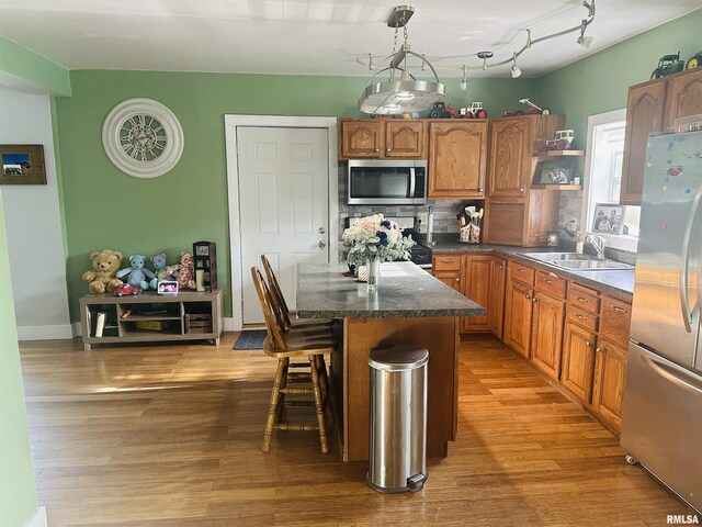 119 S Elm St, Williamsfield, IL 61489 - kitchen featuring appliances with stainless steel finishes, a breakfast bar, brown cabinets, a sink, and light wood-style floors