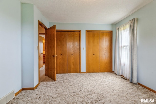 404 10th St, Lowden, IA 52255 - unfurnished bedroom featuring carpet, multiple closets, baseboards, and a textured ceiling