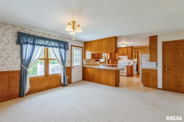 404 10th St, Lowden, IA 52255 - kitchen featuring white appliances, brown cabinetry, wallpapered walls, a peninsula, and light countertops