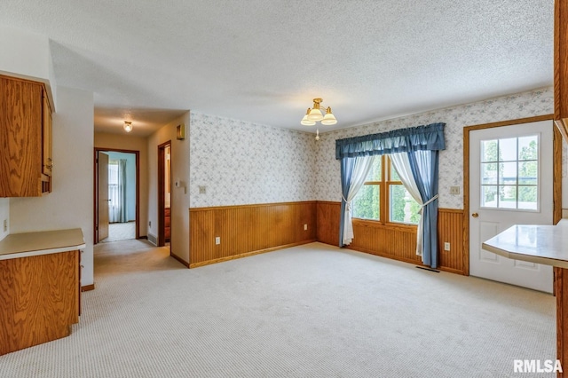 404 10th St, Lowden, IA 52255 - unfurnished dining area with wainscoting, light colored carpet, wallpapered walls, a textured ceiling, and a chandelier