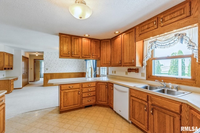 404 10th St, Lowden, IA 52255 - kitchen with white dishwasher, a sink, wallpapered walls, brown cabinets, and a textured ceiling