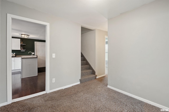 716 10th St, De Witt, IA 52742 - carpeted empty room featuring a sink, stairway, and baseboards