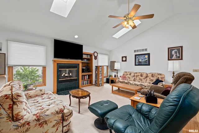 5142 Fillmore Ct, Davenport, IA 52806 - living area featuring a skylight, light colored carpet, a tiled fireplace, a ceiling fan, and high vaulted ceiling