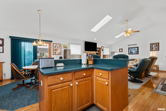 5142 Fillmore Ct, Davenport, IA 52806 - kitchen featuring light wood-type flooring, a skylight, dark countertops, vaulted ceiling, and open floor plan