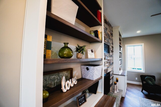 6654 Meghan Ave, Bettendorf, IA 52722 - detailed view of wood finished floors, baseboards, a stone fireplace, built in shelves, and recessed lighting