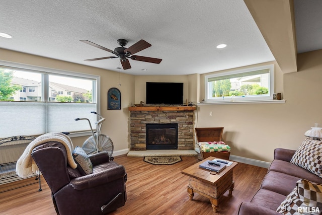 3608 Glengevlin Way, Bettendorf, IA 52722 - living area with baseboards, ceiling fan, a textured ceiling, a fireplace, and wood finished floors