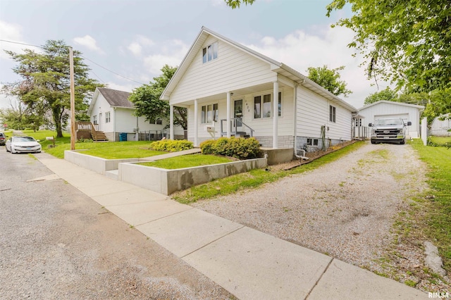 1408 Newton Ave, Johnston City, IL 62951 - view of front of house featuring an outdoor structure, a front lawn, gravel driveway, covered porch, and a detached garage