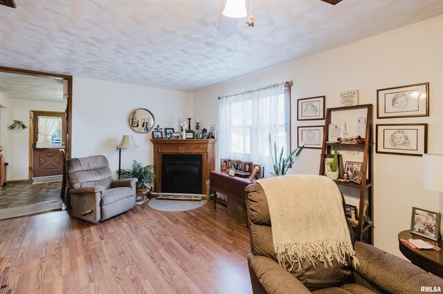 1408 Newton Ave, Johnston City, IL 62951 - living area with wood finished floors, a textured ceiling, a glass covered fireplace, and a ceiling fan