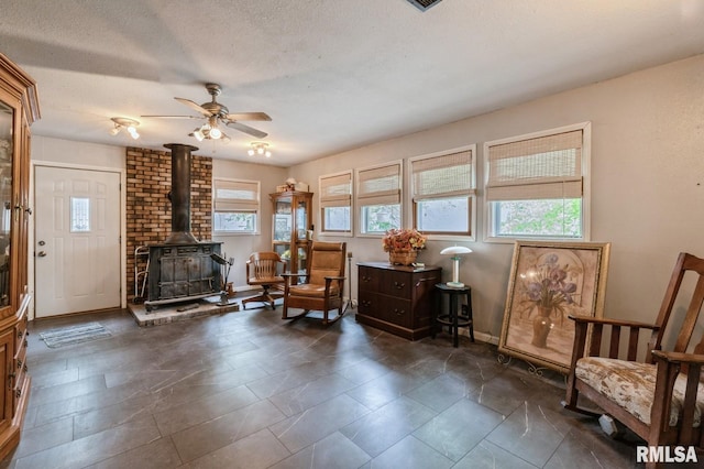201 4th St, New Boston, IL 61272 - living area featuring a wood stove, ceiling fan, a textured ceiling, and baseboards