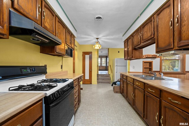 519 2nd St, Camanche, IA 52730 - kitchen featuring range with gas cooktop, under cabinet range hood, a sink, light countertops, and freestanding refrigerator