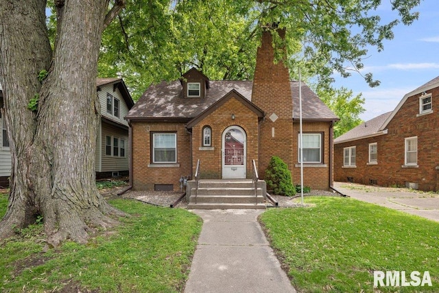 2446 16th Ave, Moline, IL 61265 - tudor-style house with brick siding, a chimney, a front lawn, and a shingled roof