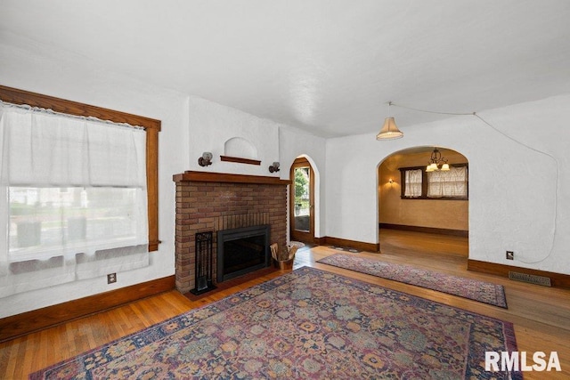 2446 16th Ave, Moline, IL 61265 - living area featuring arched walkways, baseboards, wood finished floors, and a brick fireplace