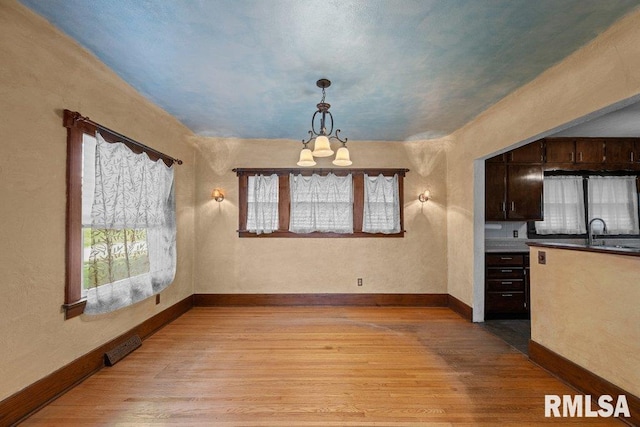 2446 16th Ave, Moline, IL 61265 - unfurnished dining area with a chandelier, light wood finished floors, and baseboards