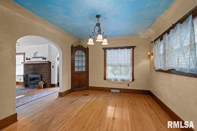 2446 16th Ave, Moline, IL 61265 - unfurnished dining area with arched walkways, wood finished floors, baseboards, a chandelier, and a fireplace