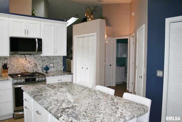 4011 Prairie Ln, Bettendorf, IA 52722 - kitchen with appliances with stainless steel finishes, a towering ceiling, white cabinetry, a center island, and tasteful backsplash