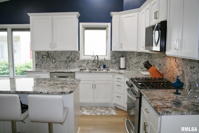 4011 Prairie Ln, Bettendorf, IA 52722 - kitchen with stainless steel appliances, a sink, white cabinets, and backsplash