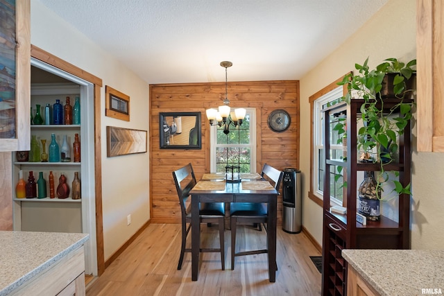 905 1st St, Camanche, IA 52730 - dining area featuring a chandelier, light wood-style flooring, wood walls, and baseboards
