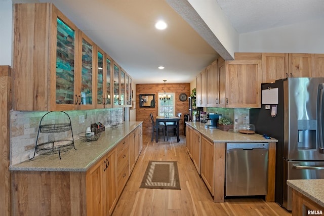 905 1st St, Camanche, IA 52730 - kitchen with appliances with stainless steel finishes, light wood-type flooring, glass insert cabinets, light stone countertops, and pendant lighting