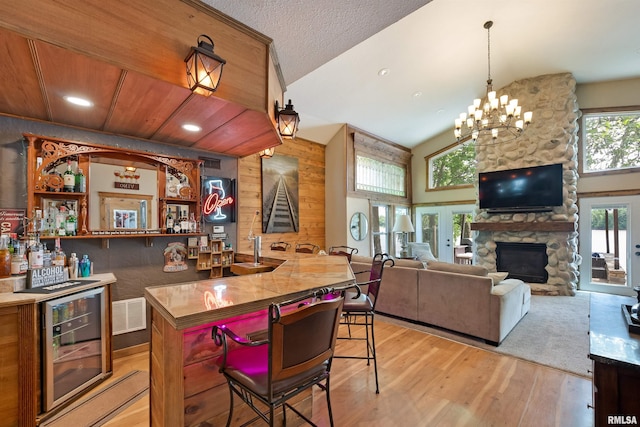 905 1st St, Camanche, IA 52730 - kitchen featuring wine cooler, light wood-style floors, a fireplace, brown cabinets, and a breakfast bar