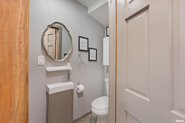905 1st St, Camanche, IA 52730 - half bathroom with toilet, a textured wall, vanity, and wood finished floors