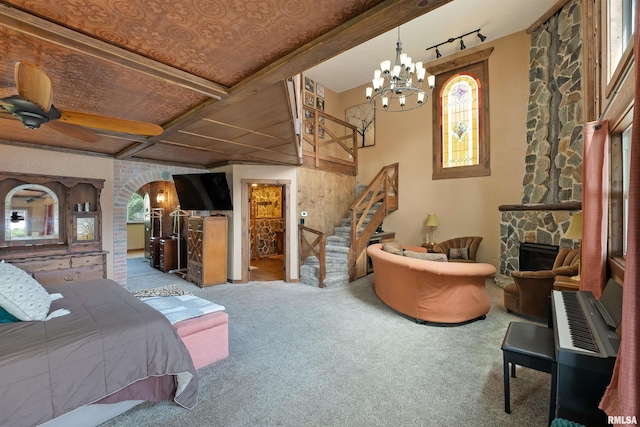 905 1st St, Camanche, IA 52730 - bedroom featuring carpet, a chandelier, a stone fireplace, arched walkways, and beam ceiling
