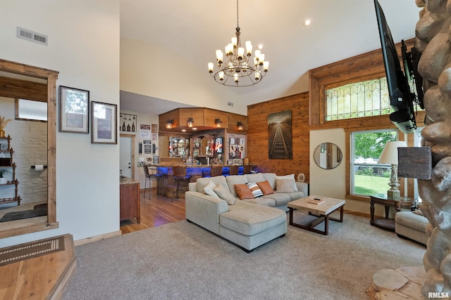 905 1st St, Camanche, IA 52730 - living area featuring high vaulted ceiling, a chandelier, carpet flooring, and wooden walls
