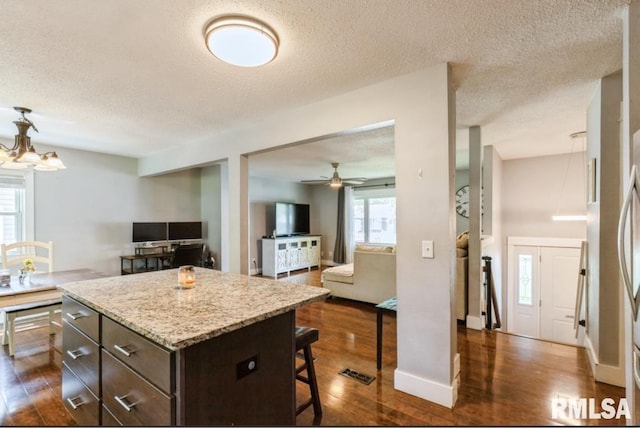 3071 S Hampton Dr, Bettendorf, IA 52722 - kitchen with a kitchen breakfast bar, dark brown cabinetry, a textured ceiling, dark wood finished floors, and ceiling fan