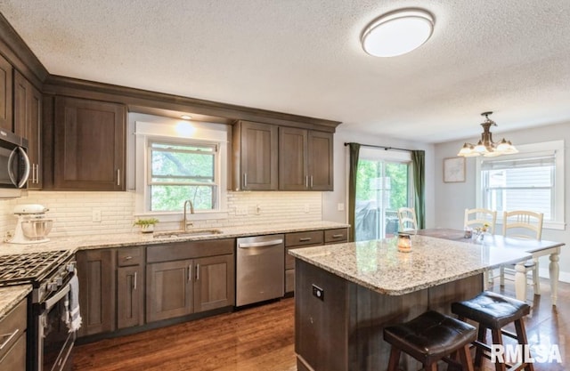 3071 S Hampton Dr, Bettendorf, IA 52722 - kitchen featuring appliances with stainless steel finishes, a sink, a textured ceiling, a chandelier, and dark wood-type flooring