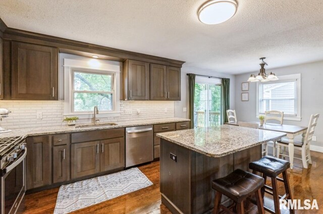 3071 S Hampton Dr, Bettendorf, IA 52722 - kitchen featuring appliances with stainless steel finishes, a textured ceiling, dark wood-style floors, a chandelier, and a center island