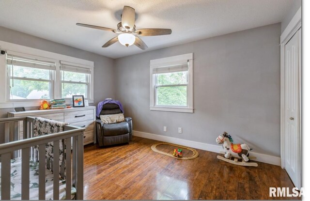 3071 S Hampton Dr, Bettendorf, IA 52722 - bedroom featuring multiple windows, wood finished floors, a nursery area, and a ceiling fan