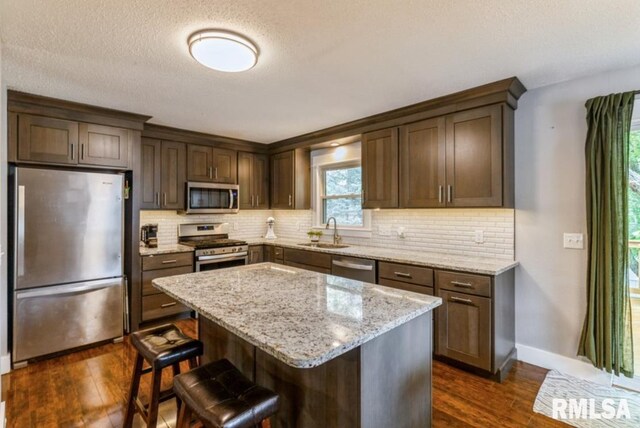 3071 S Hampton Dr, Bettendorf, IA 52722 - kitchen with stainless steel appliances, dark wood-style floors, tasteful backsplash, light stone countertops, and a breakfast bar area