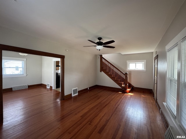 1122 E Colorado St, Davenport, IA 52803 - unfurnished living room with dark wood-type flooring, stairway, ceiling fan, and baseboards