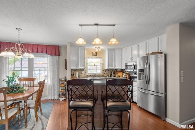 1415 W 59th St, Davenport, IA 52806 - kitchen featuring stainless steel appliances, a chandelier, a sink, white cabinets, and backsplash