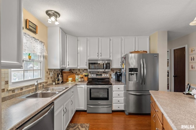 1415 W 59th St, Davenport, IA 52806 - kitchen with stainless steel appliances, a sink, white cabinetry, light countertops, and a textured ceiling