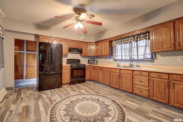 627 5th Ave S, Clinton, IA 52732 - kitchen with black appliances, under cabinet range hood, a sink, a textured ceiling, and a ceiling fan