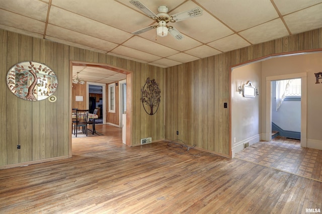 627 5th Ave S, Clinton, IA 52732 - unfurnished room featuring wood walls, wood finished floors, arched walkways, ceiling fan, and baseboards