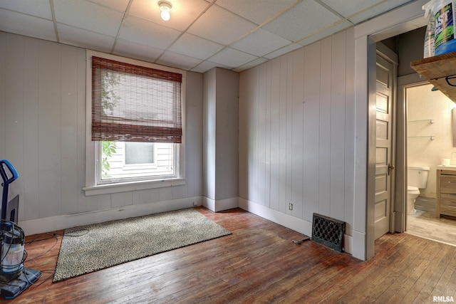 627 5th Ave S, Clinton, IA 52732 - unfurnished room featuring wood-type flooring, a drop ceiling, and wooden walls